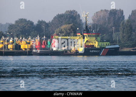 Nave di Coastwatch olandese nei pressi di stoccaggio di marine boe su la mattina presto dopo foggy sunrise in autunno Foto Stock