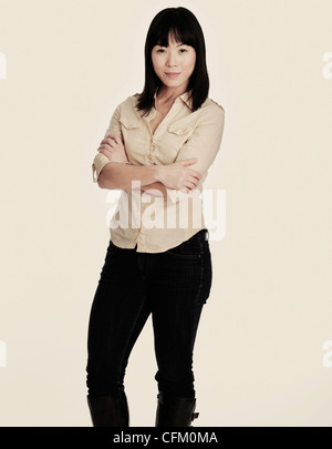 Metà adulto donna sorridente in piedi, studio shot Foto Stock