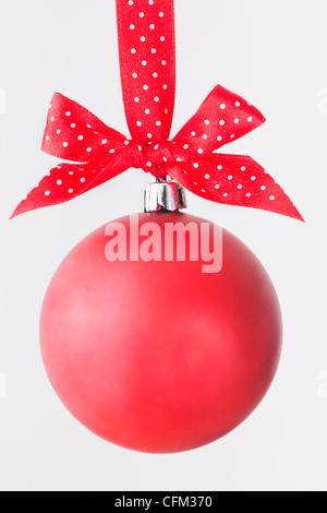 Studio shot di rosso ornamento di Natale appeso sul red ribbon maculato Foto Stock