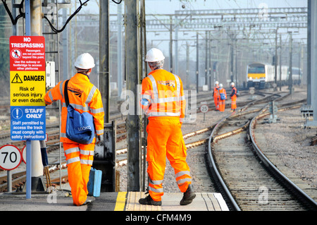 Lavoratori di Network Rail indumenti di sicurezza ad alta visibilità e elmetti sulla piattaforma ferroviaria gruppo di lavoratori su binari oltre il treno lontano Essex Inghilterra Regno Unito Foto Stock