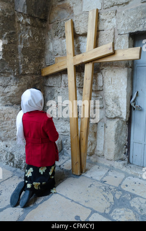 Pellegrino in ginocchio di fronte a due croci di legno presso il Santo Sepolcro, la Città Vecchia di Gerusalemme, Israele, Medio Oriente Foto Stock