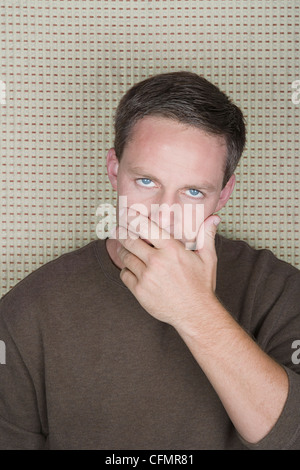 Ritratto in studio di uomo maturo che copre la bocca con la mano Foto Stock