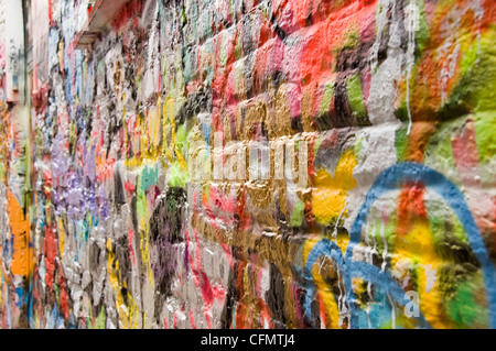 Chiudere orizzontale della miriade di colori e texture che copre una parete di mattoni giù il vicolo di Graffiti Werregaran Straat a Gand. Foto Stock