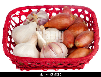 Gli scalogni e l'aglio in un cesto di rosso isolato su bianco. Foto Stock