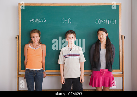 Stati Uniti, California, Los Angeles, due studentesse e schoolboy in piedi contro la lavagna con professione nomi scritti sopra Foto Stock
