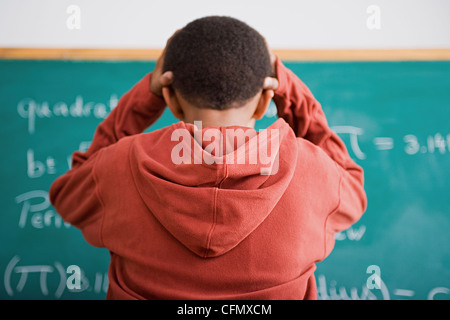 Stati Uniti, California, Los Angeles, frustrato schoolboy in piedi di fronte di Blackboard Foto Stock