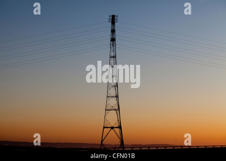 Un traliccio di elettricità che trasportano energia elettrica al tramonto di sera sul fiume Severn come visto dal lato inglese del fiume Foto Stock