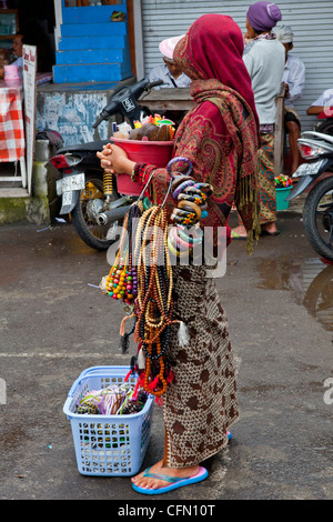 Donna vendita di filo di perle e offrendo nella parte anteriore di un tempio, a Sulawesi, Java, Bali, Pacifico del Sud, Indonesia, Asia del Sud Foto Stock