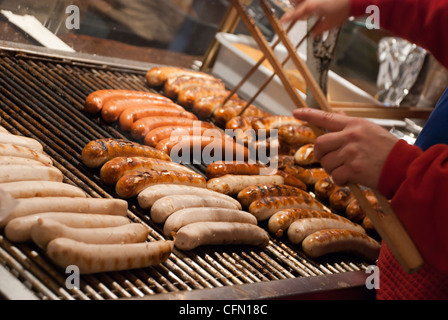 Il bratwurst (tedesco salsiccia) cottura alla griglia in un mercatino di Natale Foto Stock