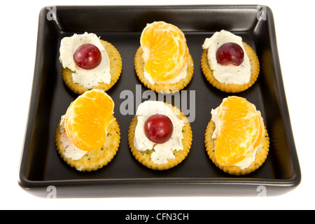 Foto di alcuni cracker con il formaggio su una piastra nera Foto Stock