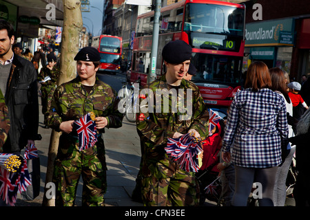 Parte dell'esercito di tempo cadetti dando fuori Unione Jack flag per gli acquirenti prima di una parata militare Foto Stock