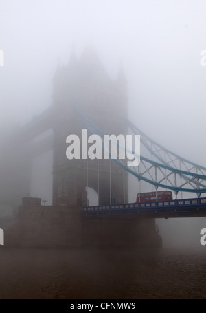 Double decker bus crossing Tower Bridge in London smog Foto Stock