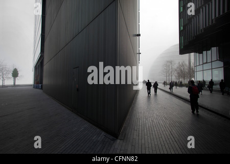 Pendolari a piedi attraverso gli edifici di più di Londra area di sviluppo nella nebbia mattutina Foto Stock