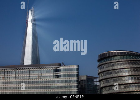 La Shard in via di completamento torreggia su Londra municipio della città in quanto rispecchia il Rising Sun in una nebbiosa mattina Foto Stock