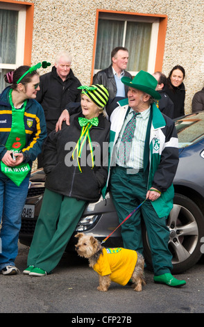 Anziani senior giovane uomo moglie guardando il giorno di San Patrizio parata in Irlanda rurale Foto Stock