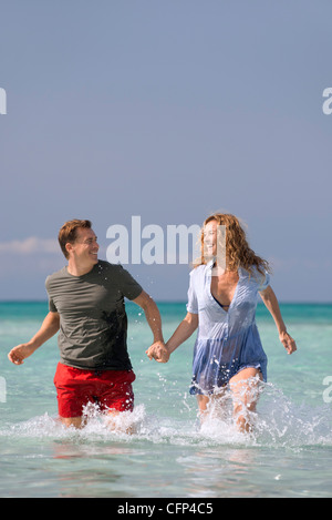 Giovane a piedi in acqua, tenendo le mani Foto Stock