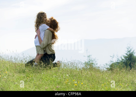 Madre e figlia abbracciando in Prato Foto Stock