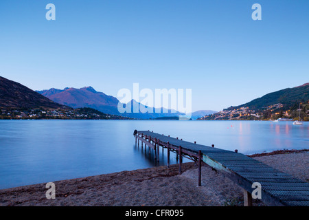 Un vecchio molo sulle rive del lago Wakatipu, Queenstown, Otago, Nuova Zelanda, e Queenstown in distanza. Foto Stock