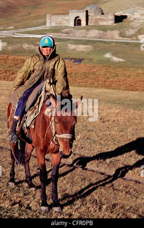 Giovane cavaliere di fronte al Tash Rabat, un xv secolo caravansarai nelle montagne del Kirghizistan del Provincia di Naryn, Asia centrale Foto Stock