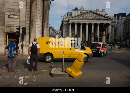 Un illusione di giallo traffico apparentemente bollard investiti da un giallo van consegna presso la banca triangolo con pilastri di Cornhill Exchange opposto, città di Londra. Foto Stock