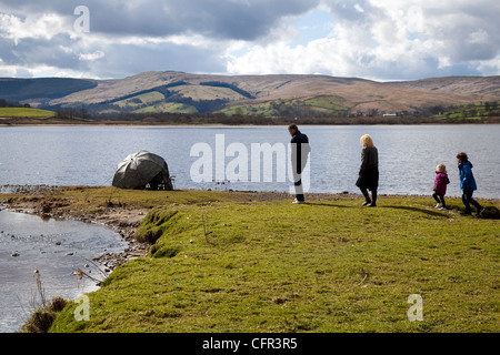 Pescatori, uomini e donne, uomo di pescatori di grossa statura sotto ombrello mimetizzata sul lago Semerwater, North Yorkshire Dales e National Park, Wensleydale, Regno Unito Foto Stock