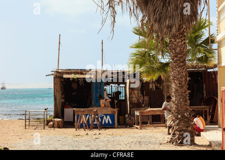 Sal Rei, Boa Vista, Isole di Capo Verde, Africa. Workshop di mobili in una capanna di legno sotto un albero di palme sul lungomare della città Foto Stock