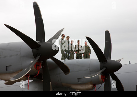 Gruppo di aviatori, incorniciata tra le pale di elica, guardando un air show dalla parte superiore di un trasportatore aereo Foto Stock