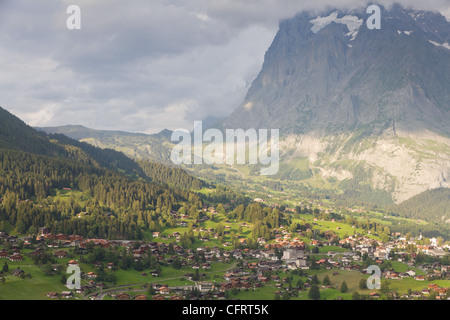 Città alpina famosa Grindelwald in valle al tramonto nella parte anteriore del Monte Eiger north face, Svizzera Foto Stock