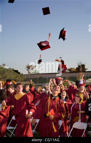 Laurea high school seniors Buttare i tappi tradizionali in aria per festeggiare la fine dell'outdoor inizio esercizi in Huntington Beach, CA. Foto Stock