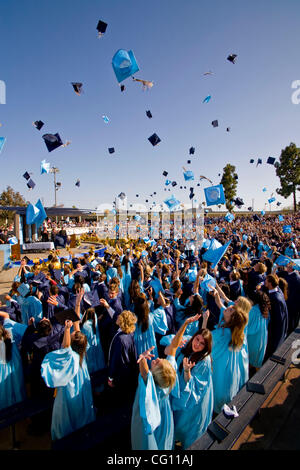 Laurea high school seniors Buttare i tappi tradizionali in aria per festeggiare la fine dell'outdoor inizio esercizi in Huntington Beach, CA. Foto Stock