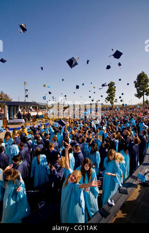 Laurea high school seniors Buttare i tappi tradizionali in aria per festeggiare la fine dell'outdoor inizio esercizi in Huntington Beach, CA. Foto Stock