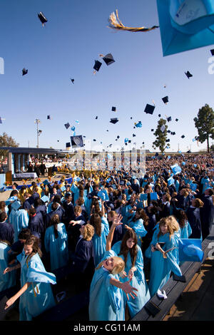 Laurea high school seniors Buttare i tappi tradizionali in aria per festeggiare la fine dell'outdoor inizio esercizi in Huntington Beach, CA. Foto Stock