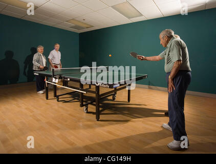 Senior uomini e donne di età compresa fra i loro anni settanta e loro 90's giocare a ping pong a seniors' impianto di atletica in pensione di comunità di Laguna boschi, CA. Modello di rilascio Foto Stock