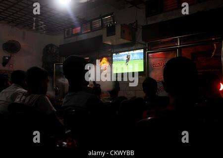 Agosto 23, 2012 - Gaza City, nella Striscia di Gaza, Territori palestinesi - giovani palestinesi guardare una partita di calcio per il FC Barcelona team contro il Real Madrid squadra durante una Supercoppa Spagnola presso il cafe a Deir al-Balah central nella Striscia di Gaza, il Ago 23, 2012 (credito Immagine: © Ashraf Amra/immagini APA/ZUMAPRESS.com) Foto Stock