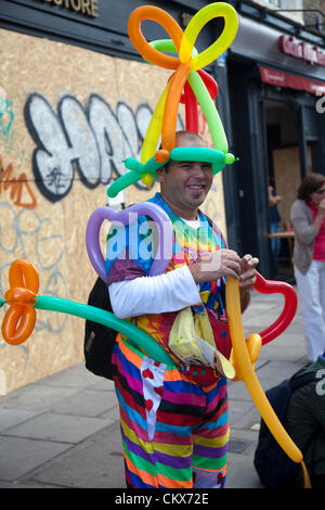 26 ago 2012, Domenica, Nottinghill Carnevale , Nottinghill Gate, London, Regno Unito - 12,50 H - uomo pubblico divertente che soffia su palloni e vestito come uno. Credito: Miguel Sobreira / Alamy Live News Foto Stock