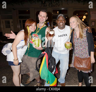 Festaioli di cocco con bevande e brandy bottiglia carnevale di Notting Hill Street di notte London Regno Unito Foto Stock