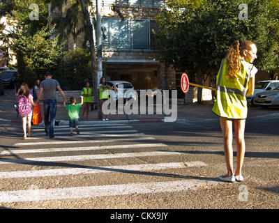 Il 27 agosto 2012. Sesto grado agli studenti di eseguire i servizi di monitoraggio del traffico e di assistere gli studenti più giovani in un accesso sicuro alla Bet-Hakerem scuola elementare. Gerusalemme, Israele. 27-Aug-2012. Bambini israeliani di tornare a scuola oggi, abolendo il tradizionale sett. 1a data, in una prima fase delle riforme avviate dal Ministero dell'istruzione mira ad accorciare le vacanze estive a 6 settimane, parzialmente alleviare i genitori di enormi spese finanziarie. Foto Stock