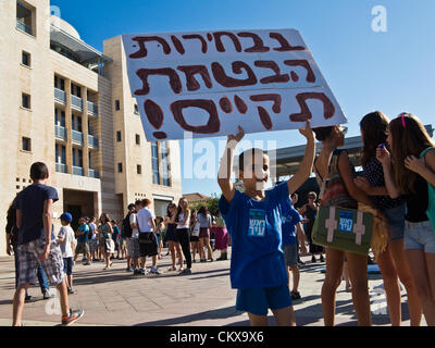 Il 27 agosto 2012. Un giovane ragazzo porta un segno in ebraico "lettura avete promesso nella tua campagna elettorale. Ora mantenere la tua promessa!" finalizzato a Sindaco Nir Barkat protestare presso la City Hall di Safra Square. Gerusalemme, Israele. 27-Aug-2012. Gli insegnanti e i genitori della Scuola Sperimentale di Gerusalemme concedere ai giovani studenti una lezione di democrazia e il diritto di protestare contro il primo giorno di scuola in municipio la dimostrazione contro anni di presunto abbandono della struttura e dei servizi. Foto Stock