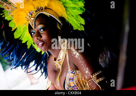 London, Regno Unito - 27 August 2012: un reveller in un costume prende riparo dalla pioggia durante l annuale carnevale di Notting Hill. Credito: pcruciatti / Alamy Live News. Foto Stock