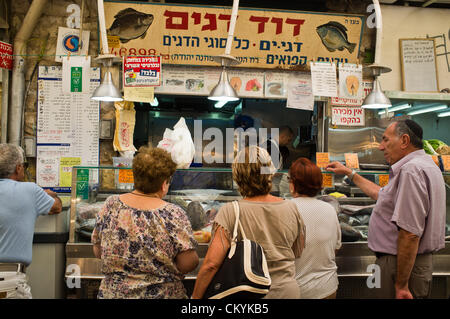 I clienti linea fino ad acquistare pesce fresco dal ben noto, David pesce, al Mahane Yehuda Market, in preparazione per Rosh Hashana,'anno ebraico. Gerusalemme, Israele. 4-Settembre-2012. Agricoltura Ministero stime più di mille tonnellate di carpe sarà trasformato in pesce Gefilte, di tradizione ebraica piatto europeo, polpette di disossata, massa, carpa, coregoni o lucci e consumato durante il prossimo ebraica vacanze alta. Foto Stock