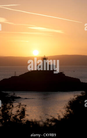 5 Settembre 2012 - Swansea - REGNO UNITO : Il sole sorge su Mumbles faro (costruito nel 1794) nella baia di Swansea questa mattina all'inizio di una calda giornata d'autunno. La 115 piede alto faro è nel processo di essere stato ridipinto da i proprietari Trinity House - quindi il ponteggio intorno all'anno 200 vecchia struttura. Foto Stock