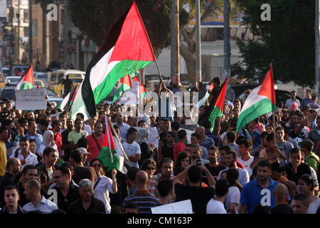 Sett. 12, 2012 - Ramallah, West Bank, Territorio palestinese - onda Palestinesi la loro bandiera nazionale durante una manifestazione di protesta contro il Protocollo di Parigi e l'accordo di Oslo, chiave di entrambi gli accordi che regolano i legami economici tra i palestinesi e gli israeliani in Cisgiordania città di Ramallah l 11 settembre 2012. Palestinesi in Cisgiordania sono state dimostrando negli ultimi dieci giorni oltre il costo della vita e in particolare il prezzo del carburante, che è passato da sei a otto sicli (da $ 1,50 a $ 2,00, 1,18 a 1,57 euro) per litro negli ultimi due mesi da solo (credito Immagine: © Issam Rimawi/APA IM Foto Stock