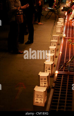 New York, NY - 11 Settembre 2012: la gente a piedi passato un memoriale vicino al World Trade Center sito in costruzione come è acceso in rosso, bianco e blu nella memoria del 9/11 attacchi 11 anni prima. Foto Stock