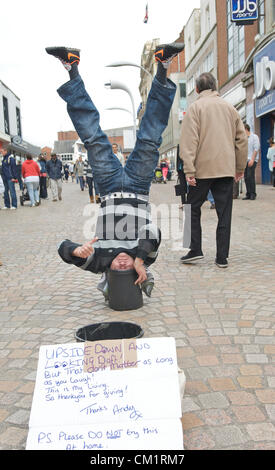 Blackpool, Regno Unito. Sabato 15 settembre 2012. Blackpool l uomo viene capovolta economia a suo vantaggio. 'Capovolto Andy' vivendo in piedi a testa in giù con la sua testa in una benna per il divertimento degli acquirenti in Blackpool Town Center. Foto Stock