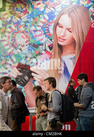 I visitatori a piedi passato grandi poster sulla seconda giornata di bi-annuale di Photokina fotografia e immagini fiera che si svolge a Colonia Germania; mercoledì 19 settembre 2012. Foto Stock