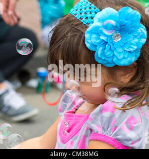 Sett. 22, 2012 - Bellmore, New York STATI UNITI - La giovane ragazza a soffiare bolle rapidamente chiude i suoi occhi quando folata di vento soffia bolle nella sua faccia, alla XXVI edizione Bellmore famiglia Street Festival. Più persone rispetto alla ben più di 120.000 che hanno partecipato alla lunga isola fair dello scorso anno erano attesi. Foto Stock