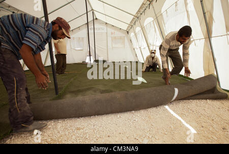 Gli uomini installare il tappeto erboso artificiale nel salvare i bambini la scuola a Zaatari Refugee Camp in Giordania il mercoledì 26 settembre, 2012. Foto Stock