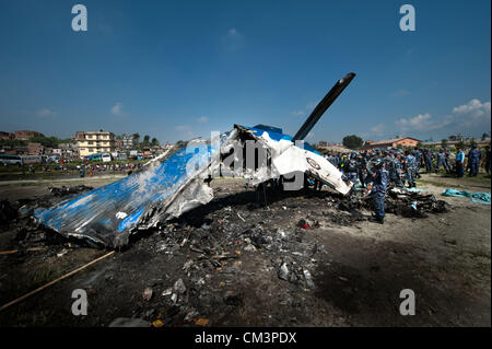 Sett. 28, 2012 - Kathmandu, Kathmandu, Nepal - Nepal una poliziotti stand intorno al relitto dell'aria sita in aereo presso il sito del crash. Un piano di trasporto del trekking nella regione dell Everest si è schiantato poco dopo il decollo del venerdì mattina in Nepal il capitale, uccidendo tutti 19 persone a bordo. Le vittime sono sette inglesi, cinque cinesi e quattro il nepalese. La doppia elica del motore aereo appartenenti al mercato domestico Sita Air si è schiantato sul terreno aperto vicino al fiume Manohara sul bordo sudoccidentale di Katmandu. La mattina il tempo era chiaro. L'autunno è il picco stagionale del turismo in Nepal. Foto Stock