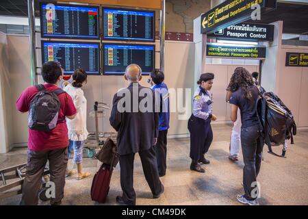 1 ottobre, 2012 - Bangkok, Thailandia - i passeggeri in partenza guardare lo stato del volo di bordo sul primo giorno di voli internazionali da Don Mueang dall'Aeroporto Internazionale di Bangkok lunedì. Don Mueang International Airport è il più piccolo dei due aeroporti internazionali che servono di Bangkok, Thailandia. Aeroporto di Suvarnabhumi, inaugurato nel 2006 è il principale. Don Mueang è stata ufficialmente aperta come un Royal Thai Air Force Base il 27 marzo 1914 e i voli commerciali ha avuto inizio nel 1924. Don Mueang Aeroporto chiuso nel 2006 in seguito all'apertura di Bangkok il nuovo aeroporto di Suvarnabhumi, e riaperto come un terminale domestico per Foto Stock