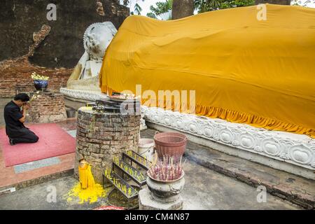 Ottobre 3, 2012 - Ayutthaya, Ayutthaya, Tailandia - un uomo prega a un Buddha reclinato di Wat Yai Chaimongkhon in Ayutthaya. Wat Yai Chaimongkhon è uno del più importante tempio di Ayutthaya e fu costruito nel 1357. Ayutthaya è l'ex capitale imperiale di ciò che è stato poi Siam, ora la Tailandia. Fondata intorno al 1350, Ayutthaya divenne la seconda capitale del Siam dopo Sukhothai. Ayutthaya la posizione tra la Cina, l'India e l'Arcipelago Malese fatta Ayutthaya il capitale commerciale dell'rgion. Dal 1700 Ayutthaya fu la città più grande del mondo con un totale di 1 milioni di abitanti. Il Ayutthaya emp Foto Stock